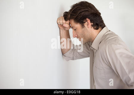 Casual worried businessman leaning head on wall Stock Photo