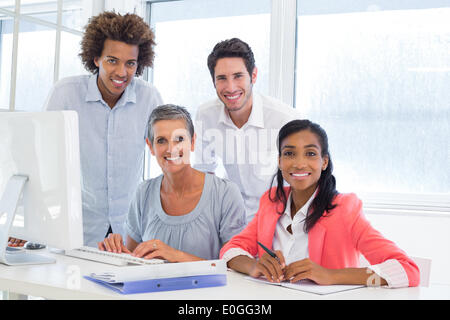 Business people working on project smiling at camera Stock Photo