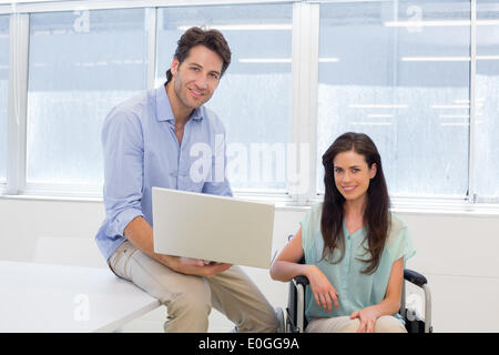 Businessman with laptop and businesswoman in wheelchair Stock Photo