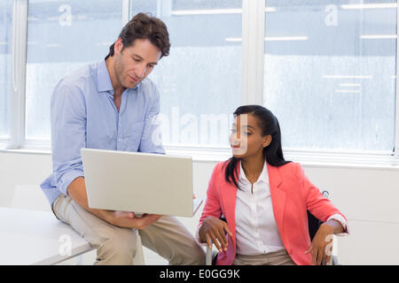 Businessman showing woman in wheelchair document on laptop Stock Photo