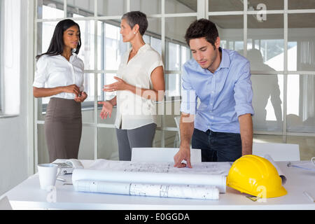 Workers talking and looking over plans Stock Photo