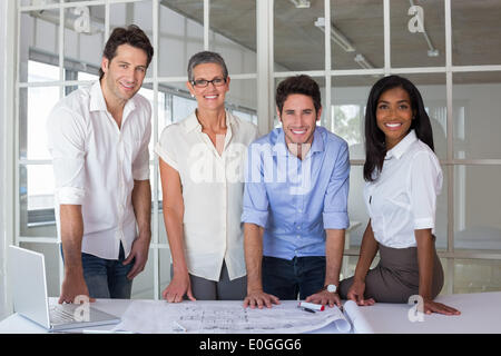 Team of architects going over blueprints smiling at camera Stock Photo