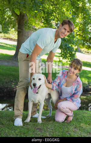 Happy couple with their labrador in the park smiling at camera Stock Photo