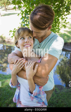 Affectionate young couple standing together in the park smiling at each other Stock Photo
