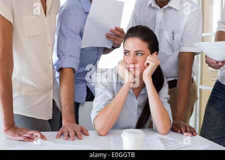 Worried businesswoman surrounded by colleagues Stock Photo