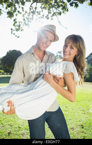 Cute blonde smiling while being picked up by boyfriend in the park Stock Photo