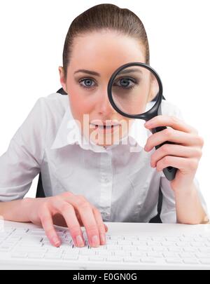 Businesswoman typing and looking through magnifying glass Stock Photo ...