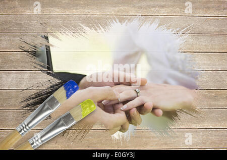 Composite image of groom placing ring on brides finger Stock Photo