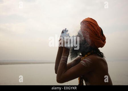 Varanasi, India. 13th May, 2014. A sadhu, or a Hindu holy man, enjoys smoking on the bank of River Ganges in Varanasi, Uttar Pradesh, India, May 13, 2014. Varanasi, an Indian city on the banks of the Ganges in Uttar Pradesh, is the holiest of the seven sacred cities in Hinduism and Jainism, and played an important role in the development of Buddhism. © Zheng Huansong/Xinhua/Alamy Live News Stock Photo
