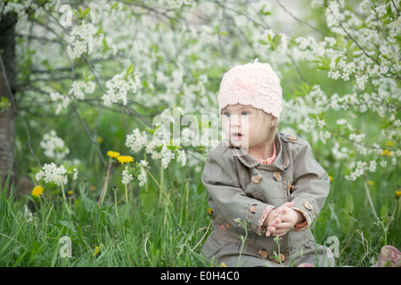 little girl with Down syndrome in the mouth pulls dandelions Stock Photo