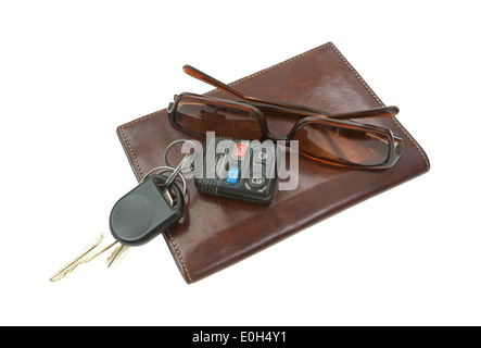 A pair of used sunglasses and car keys atop a leather billfold on a white background. Stock Photo