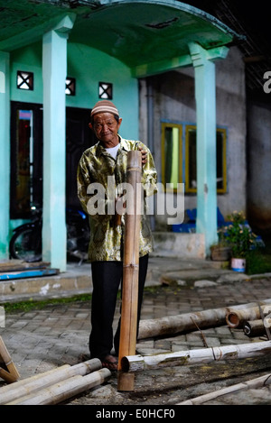 indonesian local villager working at night by the light of a single strip lamp fashioning bamboo and discarding the waste wood Stock Photo