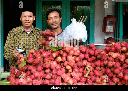 local men selling fresh rambutan fruit from a roadside stall near malang east java indonesia Stock Photo