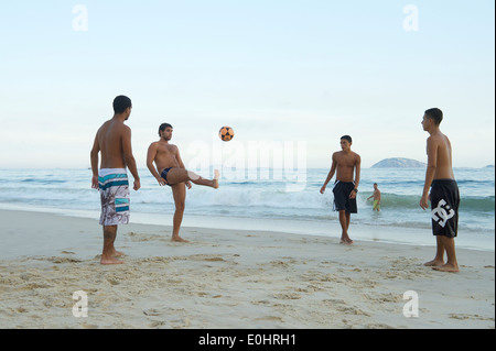 RIO DE JANEIRO, BRAZIL - APRIL 1, 2014: Group of young Brazilians play keepy uppy beach football on Ipanema Beach at Posto 9. Stock Photo