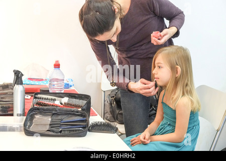 Makeup artist applies makeup to a young female model during a fashion shoot Stock Photo