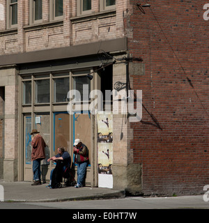 Three men standing in front of a derelict building on street, Seattle, Washington State, USA Stock Photo