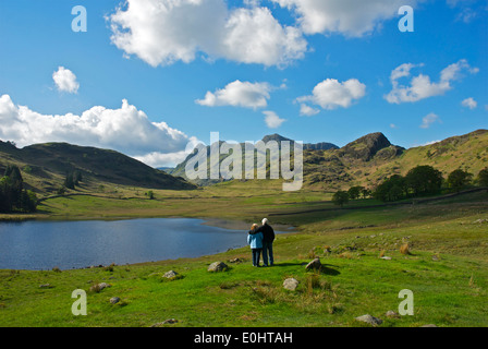 Couple looking beyond Blea Tarn to the Langdale Pikes, Little Langdale, Lake District National Park, Cumbria, England UK Stock Photo