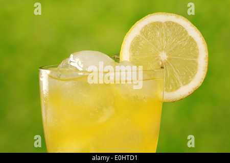 Lemonade in a glass with ice cubes, served with a lemon, plenty of copyspace Stock Photo