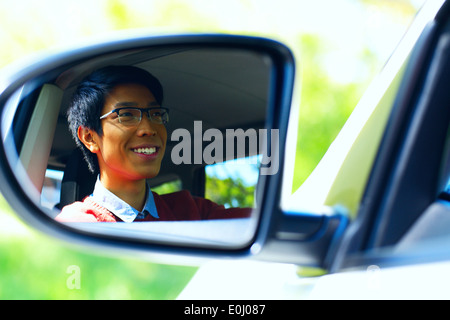 Smiling driver is reflected in mirror of car Stock Photo