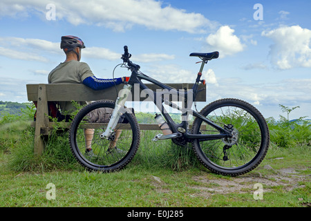 Male mountain biker resting on a wooden bench. Stock Photo