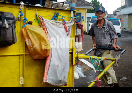 local man with cart working amongst a huge pile of fetid refuse on a public dump in malang java indonesia Stock Photo