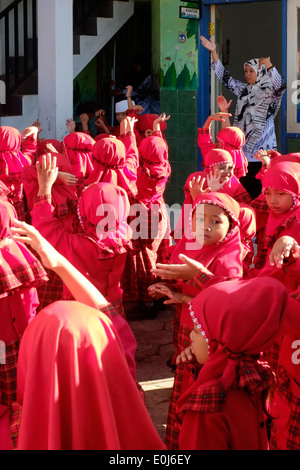 local primary school children in bright red uniforms line up in the school yard before lessons Stock Photo