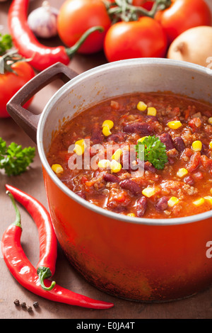 mexican chili con carne in red rustic pot with ingredients Stock Photo