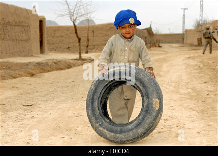 A young Afghan boy stops in the middle of the road with his tire as Soldiers assigned to 2nd Squad, 3rd Platoon, Company C., 1s Stock Photo