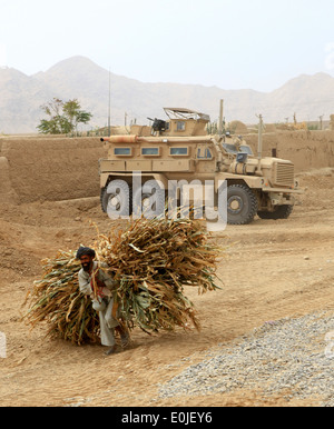 A local farmer carries corn crops past tactical vehicles with 7th Engineer Support Battalion, 2nd Marine Logistics Group (Forwa Stock Photo