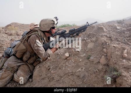 Seaman Apprentice Brian Rumbles, assigned to Golf Company, 2nd Battalion, 7th Marine Regiment, fires on two Taliban insurgents Stock Photo