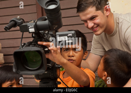 U.S. Air Force Airman 1st Class, William Branch, Armed Forces Network - Okinawa, Japan, shows a local student how to record vid Stock Photo