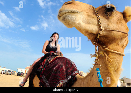Senior Airman Katerina Slivinske, from the 379th Air Expeditionary Wing, enjoys a camel ride during a cultural exchange event p Stock Photo