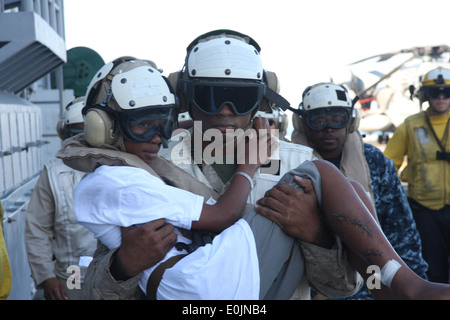 Sgt. Jarrell Williams, platoon sergeant, Combat Cargo, 24th Marine Expeditionary Unit, carries 14-year-old Lydie Augustin acros Stock Photo