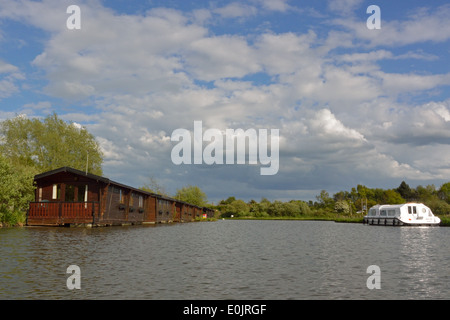 Floating holiday homes and Broads cruiser on the River Ant at Wayford Bridge, Norfolk, Broads National Park Stock Photo