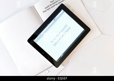 Tablet computer on book with blank pages and sheets of white paper. Stock Photo
