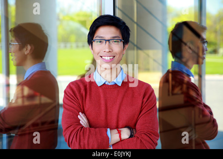 Young cheerful asian man standing with arms folded Stock Photo