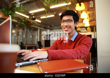 Happy asian man in glasses working on laptop in office Stock Photo