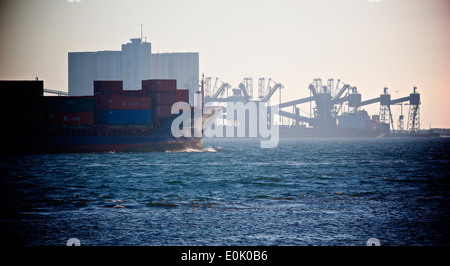 Container ship on the river Tagus (Tejo) with Trafaria grain terminal in background Lisbon Portugal western Europe Stock Photo