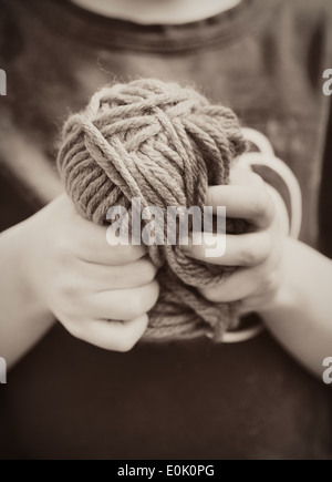 Close up of little girl holding a ball of yarn in her hands Stock Photo