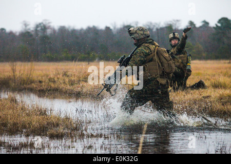 A Marine with Echo Company, 2nd Battalion, 6th Marine Regiment, refuses to allow a puddle of water from keeping him from comple Stock Photo