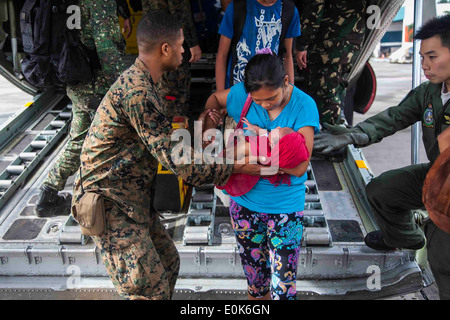 U.S. Marine Lance Cpl. Xavier L. Cannon and members of the Philippine Armed Forces help civilians displaced by Typhoon Haiyan d Stock Photo