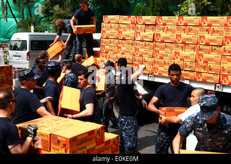 Sailors from the Arleigh Burke-class guided missile destroyer USS Lassen help unload supplies from a truck with Thai locals her Stock Photo