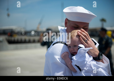 A sailor assigned to amphibious transport dock ship USS Green Bay (LPD 20) embraces a child at a homecoming ceremony at Naval B Stock Photo