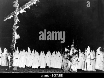 Members of the Ku Klux Klan surrounding burning cross Stock Photo