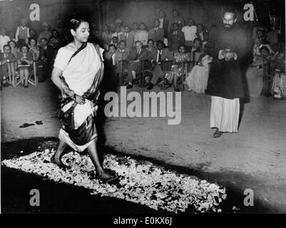 A young Indian woman walks over a bed of hot coals Stock Photo