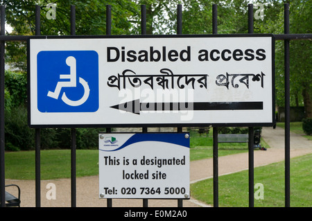 A Disabled Access sign written in English and Bengali on the railings of an East London park. Stock Photo