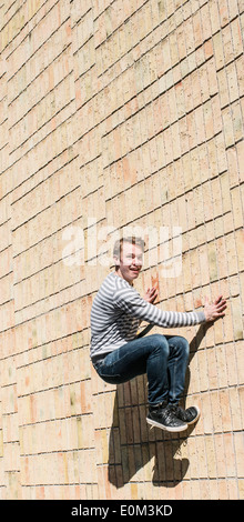 Young man doing parkour jump on brick wall. Urban scene with lifestyle moment of youth filled with energy and vitality. Stock Photo