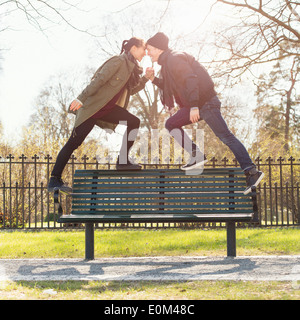 Dating young couple standing on park bench, holding hands. Stock Photo