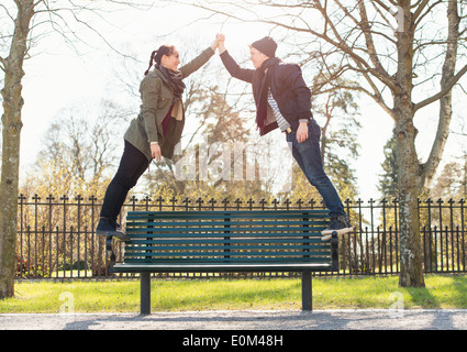 Dating young couple standing on park bench, holding hands. Stock Photo