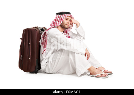 Sad Arabic man sitting on the floor with a bag behind his back Stock Photo